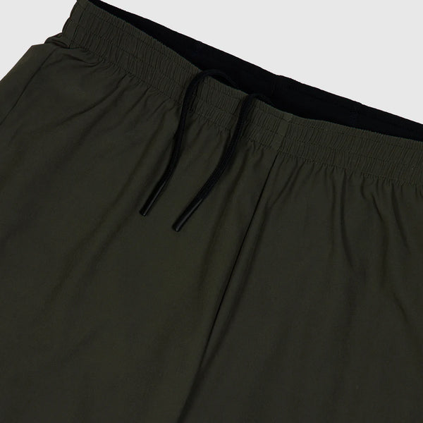 Nærbillede af Saysky 2 in 1 Pace Shorts 5'' til mænd i grøn, med elastisk linning og sort løbegang, fotograferet på en almindelig lys baggrund.