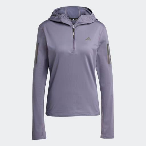 Adidas Otr Bin Hz Dame Previo er en langærmet, lyslilla træningstop med hætte, kvart lynlås foran, refleksstriber på ærmerne, brystlogo og fugttransporterende AEROREADY-stof, der giver komfort og tørhed.