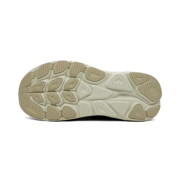 Billedet viser sålen på en Hoka Clifton 10 Dame i Sea Glass/Jadeite med en struktureret beige ydersål, der giver greb og støtte. Hoka-logoet er tydeligt synligt midt på sålen.