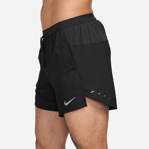 En mand, der ses fra taljen til midt på låret (set fra siden), er iført sorte Nike Stride 5" Brief-Lined Running Shorts med et reflekterende logo på venstre forben og fugttransporterende mesh nær linningen.
