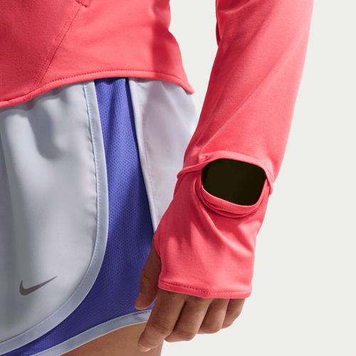 En person iført en Nike Swift UV langærmet trøje til kvinder i Sea Coral/Reflective Silver, med huller til tommelfingrene, sammen med lyslilla Nike løbeshorts. Billedet viser overkroppen og det øverste af benene.