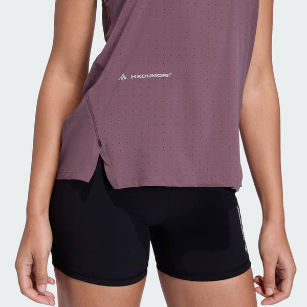 En person iført en Adidas Adi365 Hk Shafig dame singlet i mauve og sorte shorts, vist fra midt på torsoen til midt på låret, står på en almindelig lys baggrund.