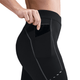 En person lægger en smartphone i sidelommen på sorte Nike Therma-FIT ADV High-Waisted 7/8 Reflective Running Leggings til kvinder med synlige sømdetaljer på en hvid baggrund.