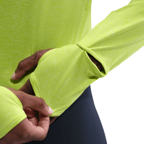 En person iført Nike Dri-FIT UV Long-Sleeve Crew-Neck Running Top, Dame, i Cyber/Htr/Reflective Silv viser tommelfingerhullet i ærmet ved at stikke tommelfingeren ind gennem åbningen. Baggrunden er hvid.