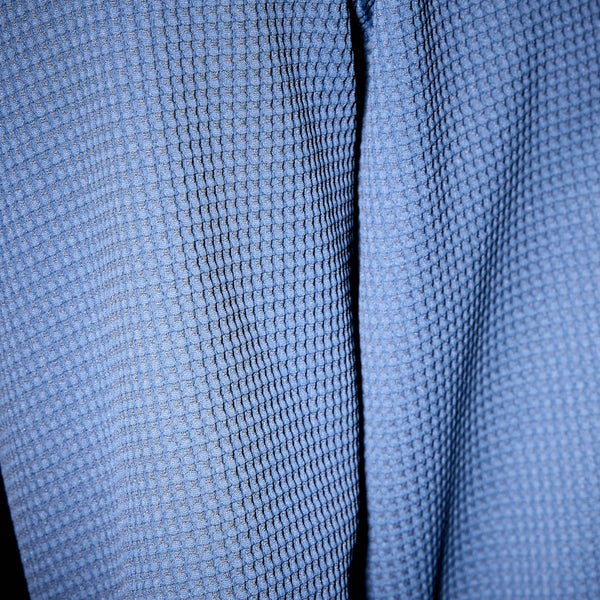 Nærbillede af Saysky Motion Waffle Long Sleeve, Herre, Blue - det blå, strukturerede stof og vaffelmønsteret fremhæves i direkte belysning og viser dybde og detaljer. Perfekt til løb og andre aktive aktiviteter.