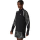 En mand er iført Asics Limited Series Lite-Show LS Top, Herre, Performance Black, en sort og grå løbetrøje med hvide detaljer, refleksdetaljer, svedtransporterende materiale og geometriske ærmemønstre, sammen med matchende shorts.
