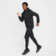 En person iført helt sort Nike-outfit - Stride Repel UV Running Jacket, Herre, Black/Black/Reflective Silv, joggers og sneakers - er fanget i gang mod en almindelig hvid baggrund.