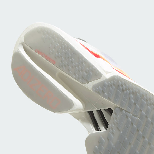 Nærbillede af den hvide ydersål på Adidas Adizero Adios Pro 4, Dame (Ftwwht/Beaora/Lucred), der viser struktureret slidbane, pink ADIZERO branding og "LIMITATION" nær hælen. Lightstrike Pro-skum giver overlegen komfort og ydeevne.