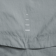 Et nærbillede af Nike Repel UV Running Jacket, Herre i Smoke Grey/Reflective Silv, viser lysegråt stof med en lodret søm og fem hvide stingmærker - hvilket understreger dens UV-beskyttende egenskaber.