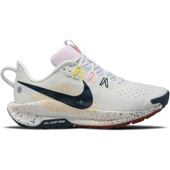Nike Pegasus Trail 5 til kvinder har en overdel i Summit White med en sort Swoosh, flerfarvede snørebånd, ReactX-mellemsål og en hvid sål med gule, orange og røde pletter. "NIKE TRAIL ATC" står på siden af sålen.