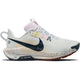 Nike Pegasus Trail 5 til kvinder har en overdel i Summit White med en sort Swoosh, flerfarvede snørebånd, ReactX-mellemsål og en hvid sål med gule, orange og røde pletter. "NIKE TRAIL ATC" står på siden af sålen.