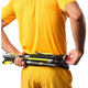 En person i gult holder en foldet vandrestav og et sort Salomon Pulse Løbebælte, Unisex, med den ene hånd trukket i bæltets lynlås bag ryggen.