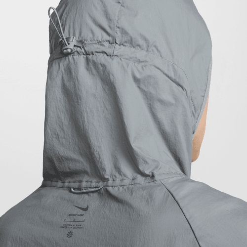 Et nærbillede af bagsiden af Nike Repel UV Running Jacket, Herre i Smoke Grey/Reflective Silv viser hætten med snøre og stopper. Bæreren vender ansigtet væk, og "UV-beskyttelse" vises på denne løbejakke herre.