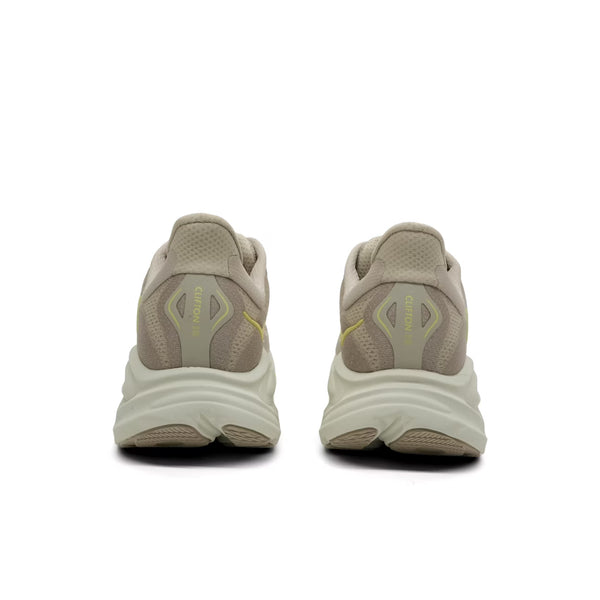 Et par Hoka Clifton 10 herre løbesko i Raw Linen/Stone vises bagfra på en hvid baggrund og viser letvægtskomfort, en tyk bølget hvid sål, mesh-hæl med gul accent og "Clifton 10"-branding.