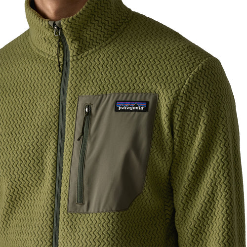 Nærbillede af en person iført Patagonia R1 Air Jacket til mænd i Caper Green med et struktureret mønster og en brystlomme med lynlås og Patagonia-logo.