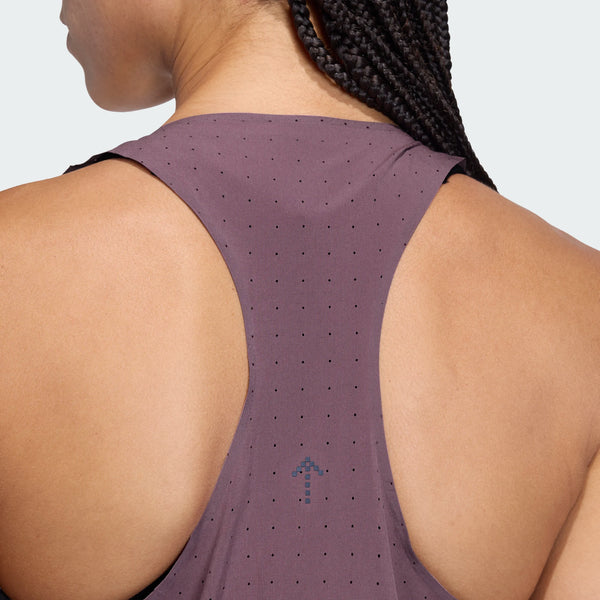 Nærbillede af en persons øverste del af ryggen iført Adidas Adi365 Hk Singlet, Dame, Shafig - med et lilla perforeret design med en blå pil. Deres flettede hår og lysebrune hud supplerer singlettens svedtransporterende komfort.