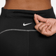 En person åbner en lynlåslomme på Nike Therma-FIT ADV High-Waisted 7/8 Reflective Running Leggings til kvinder i Black/Dk Smoke Grey, med hvide syninger og et synligt Nike-logo under linningen.