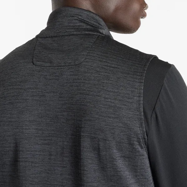 Et nærbillede viser den øverste del af ryggen, nakken og en del af ansigtet på en person iført New Balance Heat Grid Vest, Herre, i sort/skifergrå over en sort langærmet skjorte.