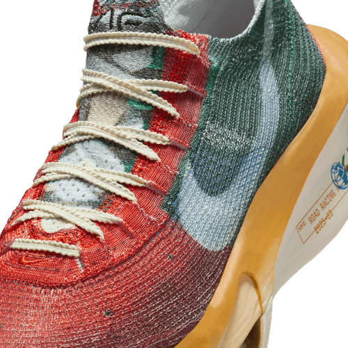 Et nærbillede af Nike Alphafly Next% 3 Prm (Herre) i Multi-Color/Clear-Starfish-Aloe Verde viser hvide snørebånd, en lyseblå swoosh, ZoomX-skum og en blå globusgrafik med tekst på siden.