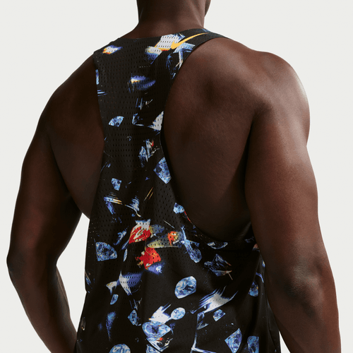 En person med mørk hud ses bagfra iført Nike Aeroswift Singlet Aop, Herre i Black/Laser Orange. Det farverige, abstrakte mønster og den svedtransporterende træningstøj skiller sig ud fra den ensfarvede, lyse baggrund.