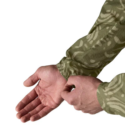 En person iført Patagonia Houdini Jacket Herre i Sand Waves/Caper Green bruger sin højre hånd til at justere det venstre ærme ved håndleddet på en hvid baggrund.