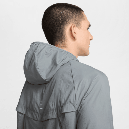 En person med kort mørkt hår ses bagfra iført Nike Repel UV Running Jacket, Herre, Smoke Grey/Smoke Grey/Reflective Silv. Baggrunden er ensfarvet og hvid.