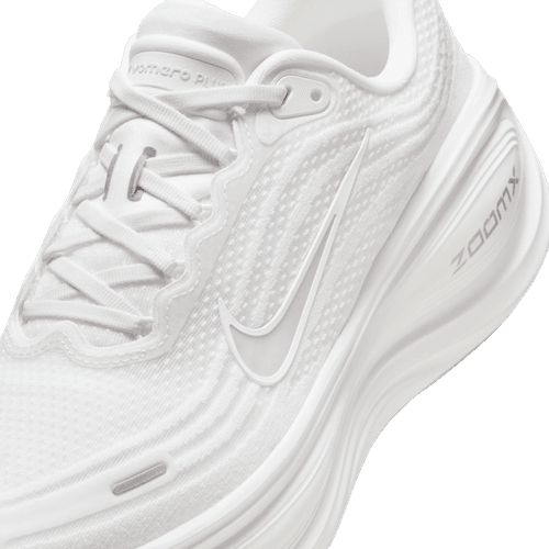 Et nærbillede af Nike Vomero Plus, Herre i White/Summit White-Photon Dust viser den ikoniske swoosh, den teksturerede overdel og "ZoomX"-branding på mellemsålen for optimal stødabsorbering.