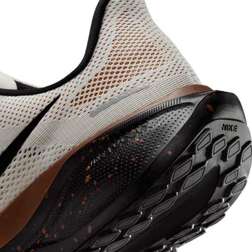 Nærbillede af hælen og ydersålen på Nike Pegasus 41, Herre i Soft Pearl/Velvet Brown-Desert Ochre, der viser åndbart mesh, struktureret sål for greb, brune pletter og responsiv ReactX-skumdæmpning.