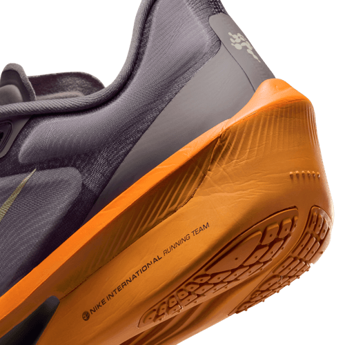 Nærbillede af hælen på en Nike Zoom Fly 6 Herre i Desert Khaki/Cave Stone-Monarch, der fremhæver den strukturerede sål og teksten "NIKE INTERNATIONAL RUNNING TEAM" på siden.