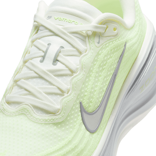 Nærbillede af en Nike Vomero Plus Dame løbesko i Sail/Metallic Silver-Barely Volt med grå Swoosh, hvide snørebånd, tekstureret mesh-overdel og et responsivt ReactX-mellemsål for øget komfort.
