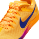 Et nærbillede af Nike Zoom Rival Distance, Herre i Citron Pulse/Indigo Burst-Hyper Violet viser det lysegule mesh, den orange sål og snørebånd, den mørkeblå swoosh og mellemsålen med gradient. Denne løbesko egner sig til mellem- og langdistanceløb.
