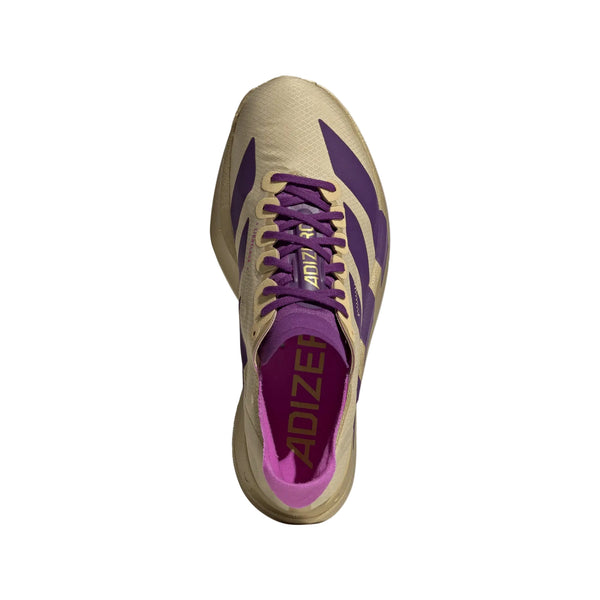 Topbillede af Adidas Adizero Adios Pro 4 Dame racesko i Sand/Ricpur/Goldmt, med lilla detaljer og snørebånd og "ADIZERO" på indersålen, fotograferet mod en hvid baggrund.