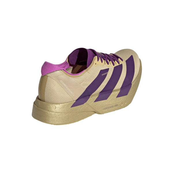 Adidas Adizero Adios Pro 4 "Dame" i Sand/Ricpur/Goldmt har en tyk sål, tre brede lilla striber og en lilla-rosa hælkappe, vist på en hvid baggrund.