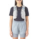En person iført sort t-shirt, lyseblå shorts, solbriller og Salomon ADV Skin 5 væskevest (Unisex, Alloy/Gray Violet/Spellbo) med vandflasker i forlommerne står klar til terrænløb mod en almindelig hvid baggrund.