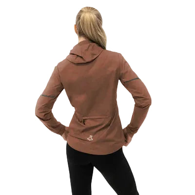 En kvinde med blondt hår i hestehale ses bagfra iført Liiteguard Aero-Tech Windbreaker, Dame, Cocoa Brown, og sorte bukser, stående med hænderne på hofterne mod en hvid baggrund.