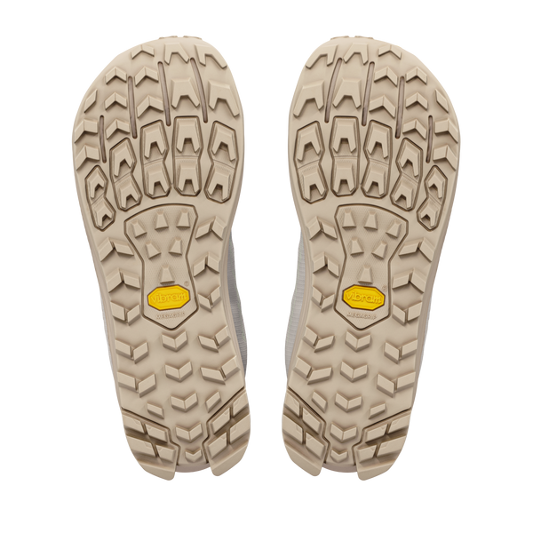 Billedet viser de beige ydersåler på Altra Lone Peak 9+ Dame i farvekombinationen Perfectly Pale/Pearl/Bark, med et robust mønster på sålen og gule Vibram-logoer i midten, fotograferet på en hvid baggrund.