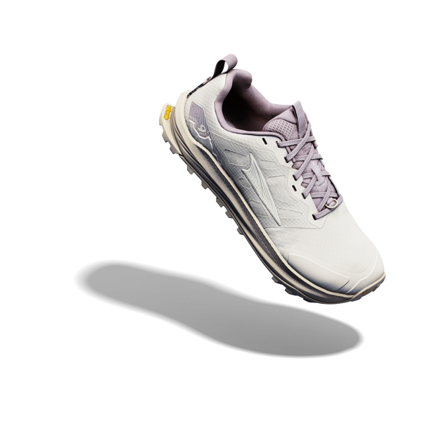 Altra Lone Peak 9+ Dame i farvekombinationen Perfectly Pale/Pearl/Bark er afbilledet oven på en hvid baggrund og har lysegråt materiale, lavendelblå detaljer og snørebånd, en struktureret sål samt Altra-logoet på siden.