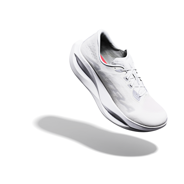 Altra Vanish Carbon 3, Herre i hvid/sølv/hvid er en hvid sportsløbesko med et elegant design, der ses svævende over en ensfarvet hvid baggrund og kaster en diskret skygge. Denne innovative konkurrencesko er fremstillet af åndbart mesh-materiale med diskrete grå og røde detaljer, hvilket gør den til det ideelle valg for seriøse løbere.