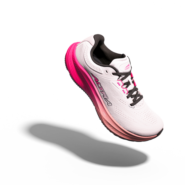 En Torin 9 Dame-løbesko fra Altra i farven Cream/Pink Flow er afbildet i luften på en hvid baggrund, hvor ALTRA-logoet er tydeligt synligt. Designet er udstyret med Altras Zero Drop-teknologi og FootShape-tåkappe.