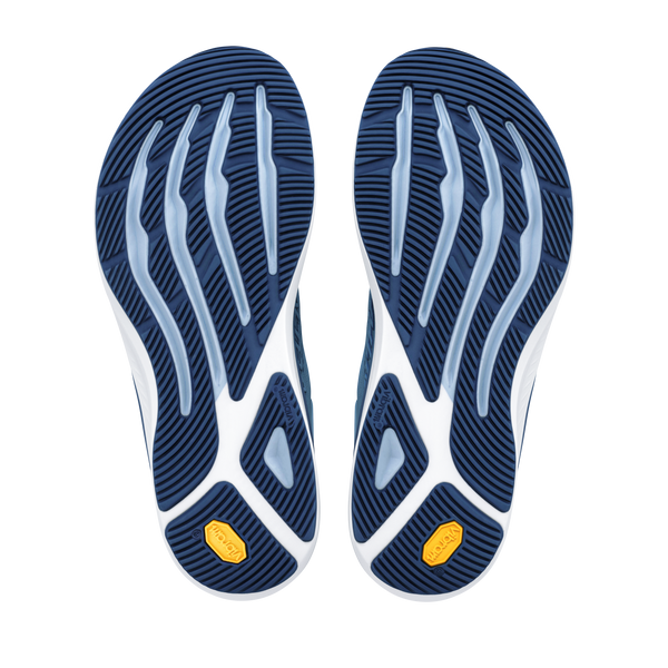 Et par Altra Torin 9 Dame-løbesko i farvekombinationen Windward Blue/White/Dark Denim med bølget, rillet sål og gule Vibram-logoer ved hælen, inspireret af Zero Drop-designet, vist side om side på en hvid baggrund.