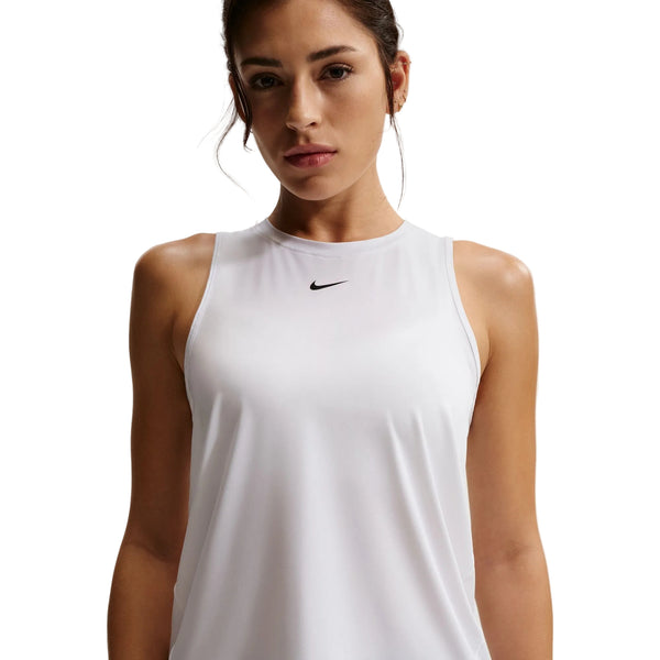 En kvinde er iført en Nike Nk One Classic Df Tank til damer i hvid/sort med et lille sort logo midt på brystet, der står på en almindelig hvid baggrund. Denne hurtigtørrende tanktop er perfekt som træningstop til damer.