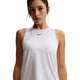 En kvinde er iført en Nike Nk One Classic Df Tank til damer i hvid/sort med et lille sort logo midt på brystet, der står på en almindelig hvid baggrund. Denne hurtigtørrende tanktop er perfekt som træningstop til damer.