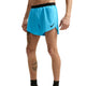 En person står iført Nike AeroSwift 4" løbeshorts med indvendig underbuks til mænd i farven Lt Current Blue/Black, med sort linning og logo. Personens tatoverede ben ses tydeligt på en ensfarvet hvid baggrund.