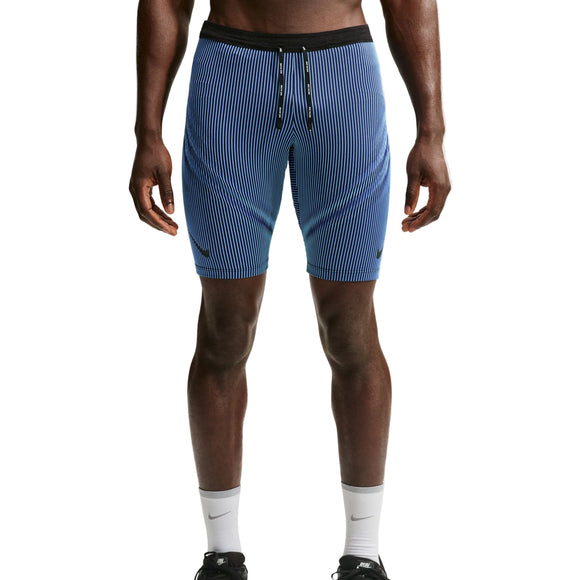 Der vises et billede af en person fra livet og ned, iført Nike AeroSwift Running Half Tights til mænd i farverne Baltic Blue/Black/Old Royal/Black, som er trukket uden på et par blå og hvide, lodret stribede sportsshorts med sort linning og snøre, kombineret med hvide sokker og sorte sportssko.