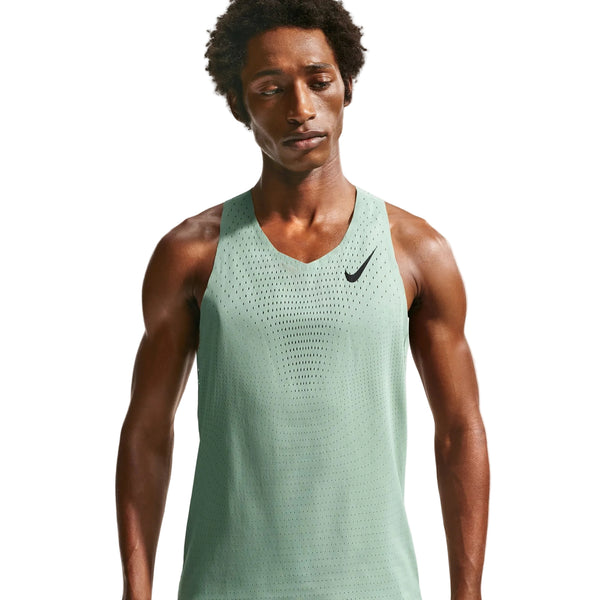 En mand i en lysegrøn Nike AeroSwift Running Singlet, Herre, Steam/Black med Dri-FIT ADV-teknologi og et sort Nike-logo på venstre bryst står på en hvid baggrund og kigger let nedad.