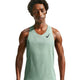En mand i en lysegrøn Nike AeroSwift Running Singlet, Herre, Steam/Black med Dri-FIT ADV-teknologi og et sort Nike-logo på venstre bryst står på en hvid baggrund og kigger let nedad.