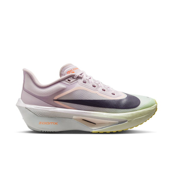Nike Zoom Fly 6 Dame i farvekombinationen Bleached Lilac/Purple Dynasty-Volt Tint har en overdel i mesh, en tyk, formstøbt ZoomX-sål, et sort Swoosh-logo og orange ZOOMX-tekst. Skoen er afbildet i profil på en hvid baggrund.