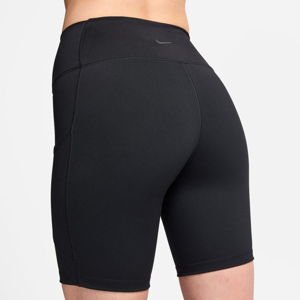 En person ses bagfra iført Nikes One High-Waisted 8" Biker Shorts With Pockets til kvinder i sort. Shortsene har synlige syninger, logo i linningen, længde midt på låret og praktiske lommer.