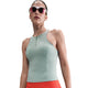 En kvinde med lyserøde solbriller bærer Nike Outdoor Bra Tank, Dame, Cannon (ærmeløs, lysegrøn, lynlås foran) og højtaljede røde leggings på en almindelig hvid baggrund.