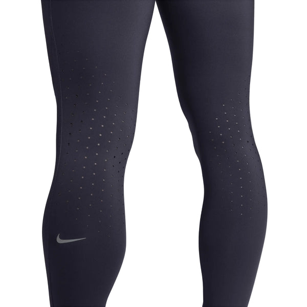 Nærbillede af en person, der bærer Nike Swift løbetights med høj talje, 7/8-længde og lommer, dame, i farven Gridiron/Reflective Silv. Disse løbetights med lommer har små, jævnt fordelt ventilationshuller på lårene og knæene for øget åndbarhed samt et diskret reflekterende Nike Swoosh-logo nederst på venstre ben. Refleksdetaljer sikrer øget synlighed under løbeture i svagt lys, mens de praktiske lommer giver ekstra funktionalitet på farten.